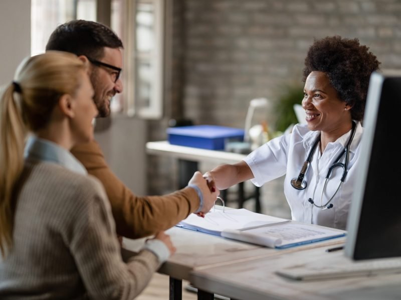 happy-african-american-doctor-greeting-a-couple-at-2023-11-27-05-20-32-utc